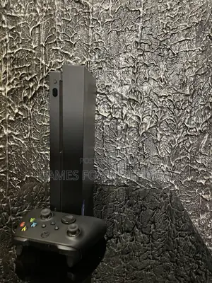 Xbox One X With a Black Controller and a Game