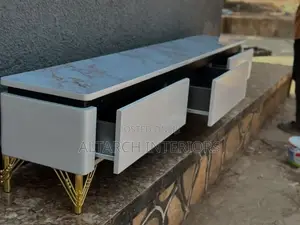 Well Furnished Tv Stand in White With a Mable on Top and Golden Legs