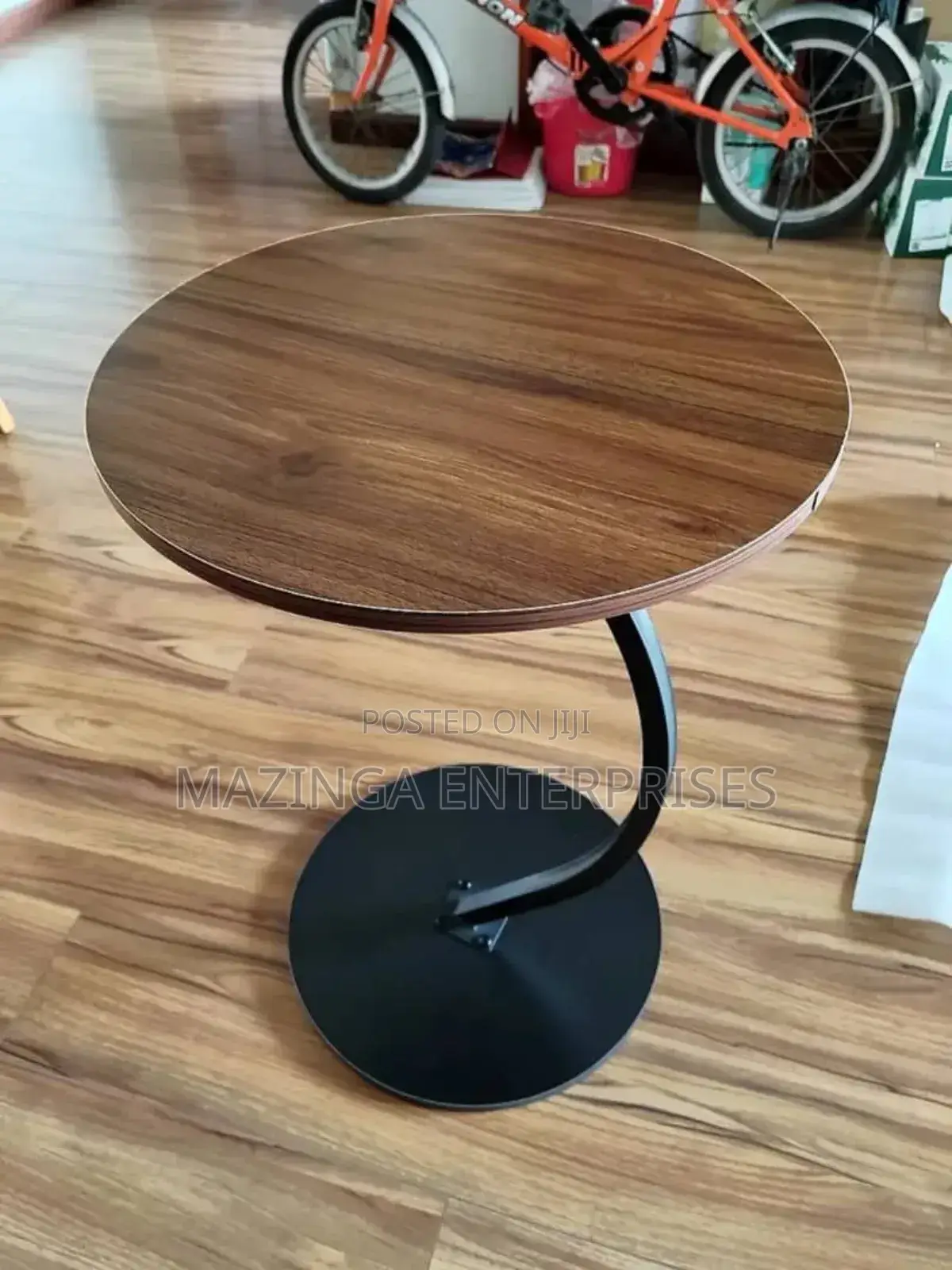 C-Shaped Side Table With a Round Wooden Top and a Black Metal Base.
