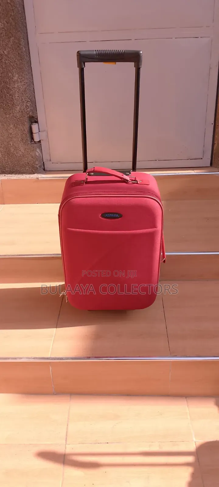 Japanese Red Soft-Sided Trolley Luggage Bag With an Extendable Handle.