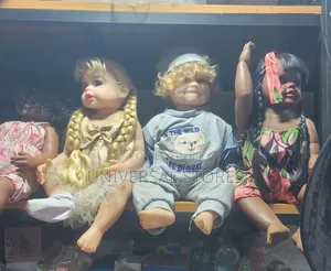 Realistic Baby Doll With Curly Blonde Hair Wearing a Grey Romper.